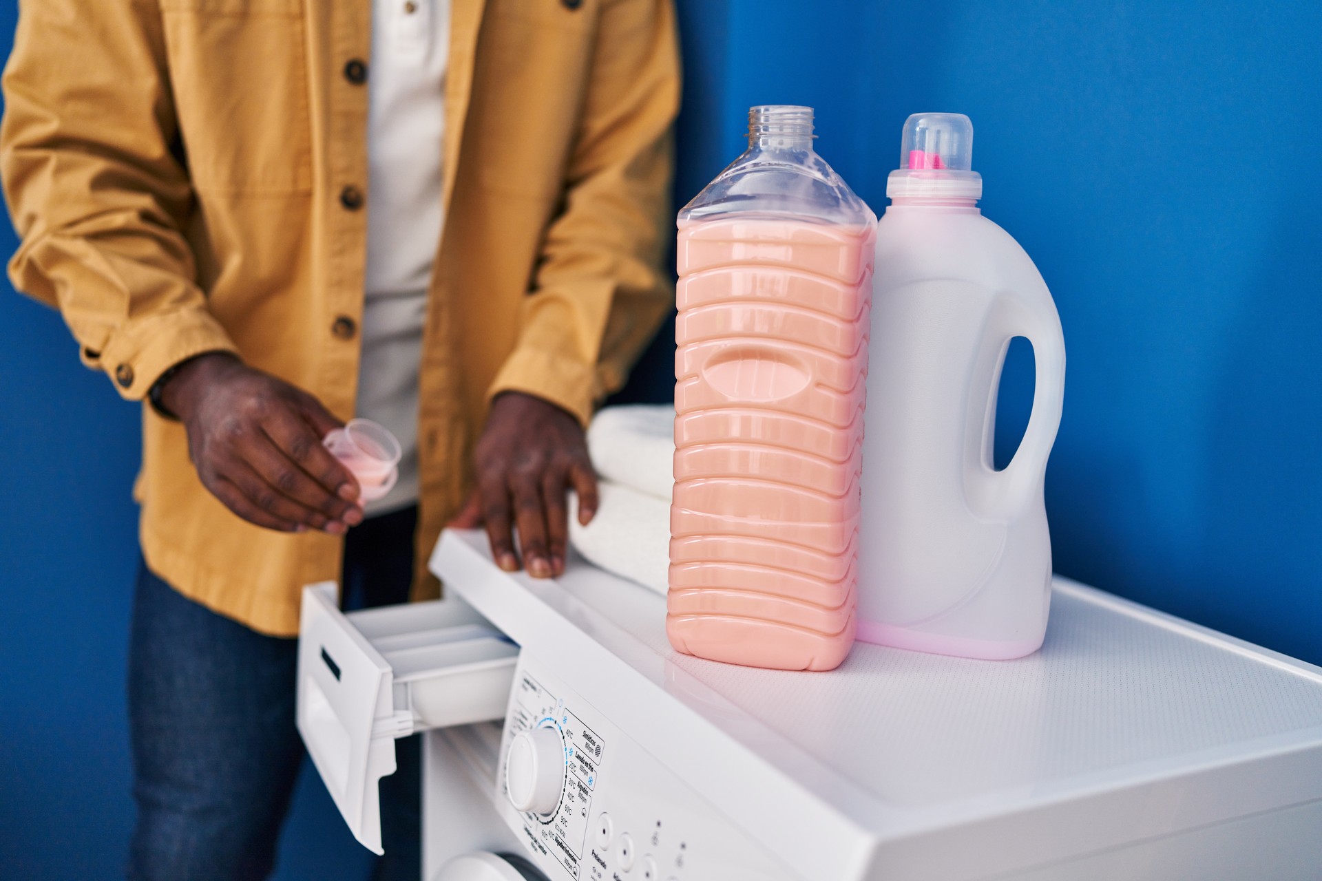 Young african american man smiling confident pouring detergent on washing machine at laundry room